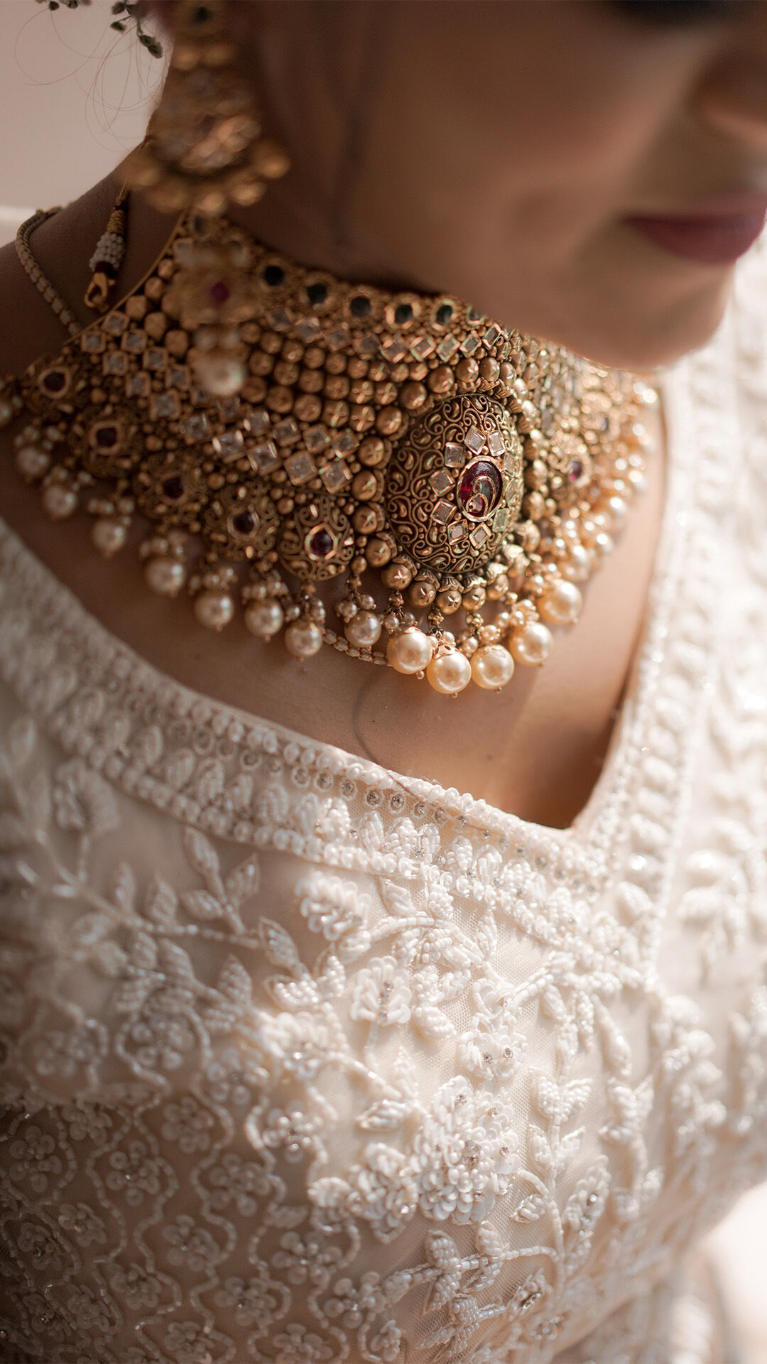 A woman wearing a beautiful pearl necklace and matching earrings with her white lehenga